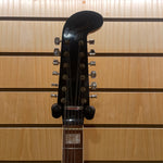 Guitar headstock with 'Coronado' branding against a wooden background