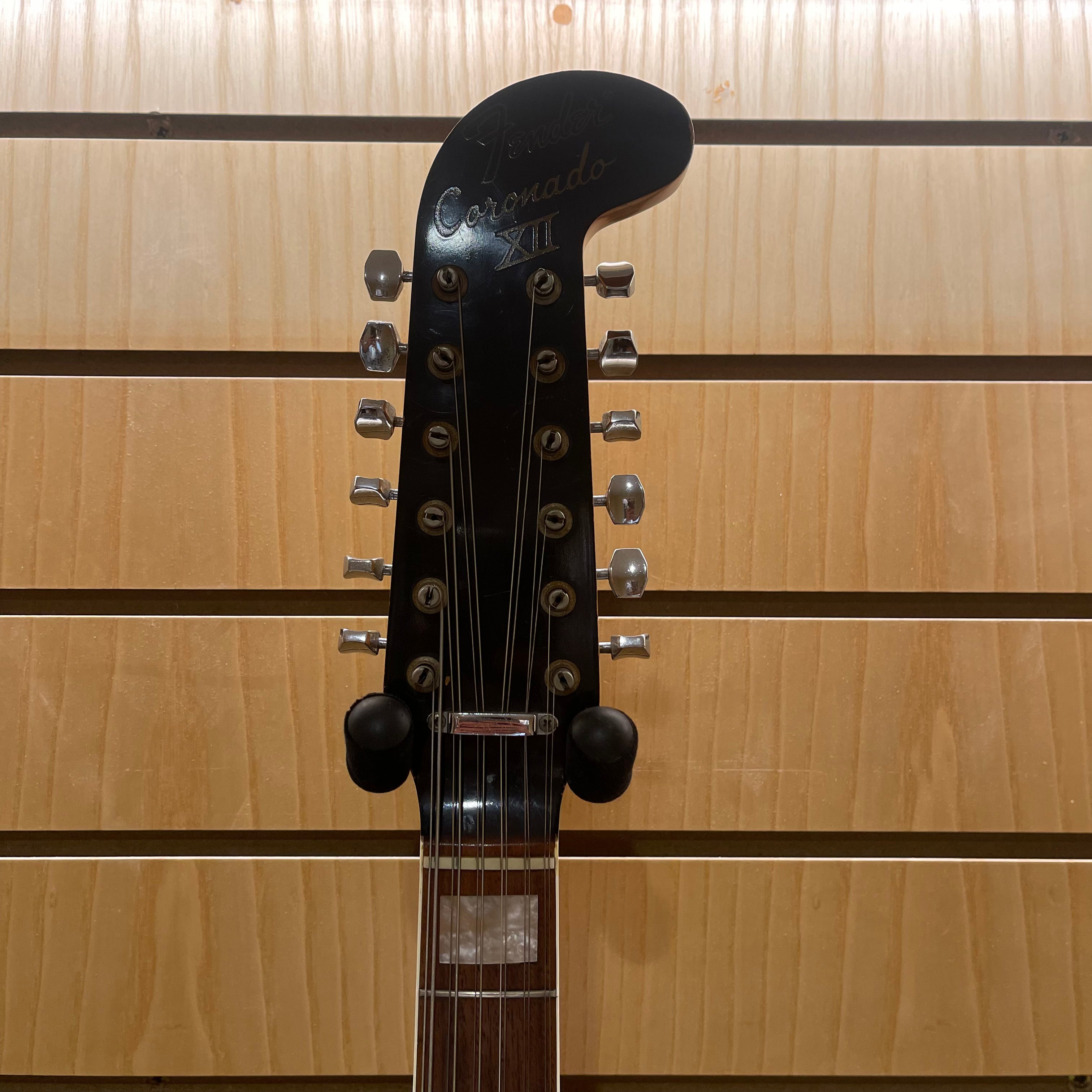 Guitar headstock with 'Coronado' branding against a wooden background
