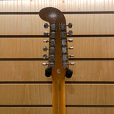 Close-up of a guitar headstock with tuning pegs against a wooden background