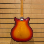 Guitar body with a sunburst finish against a wooden panel background