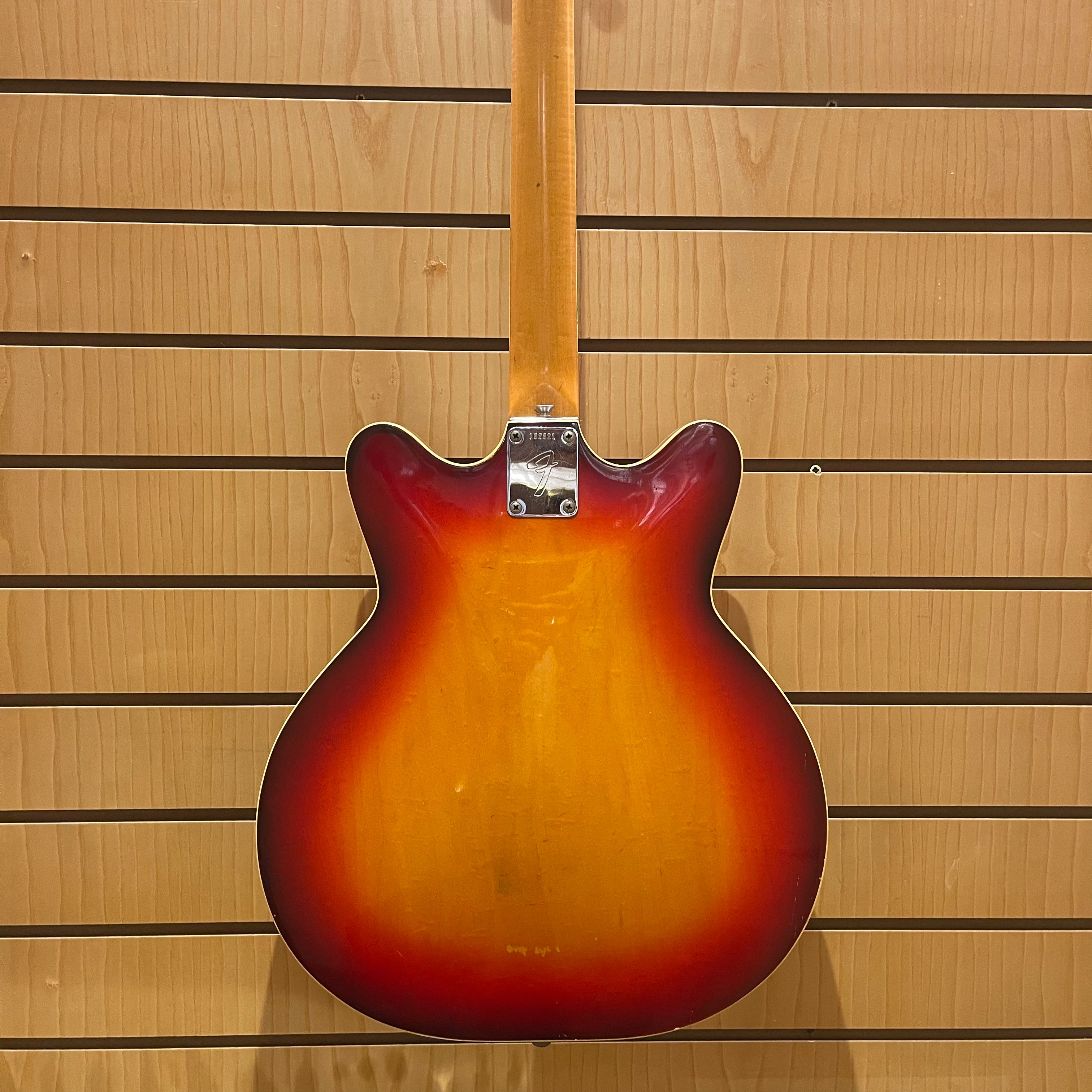 Guitar body with a sunburst finish against a wooden panel background