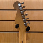 Close-up of a guitar headstock with tuning pegs on a wooden background