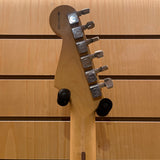 Close-up of a guitar headstock with tuning pegs on a wooden background