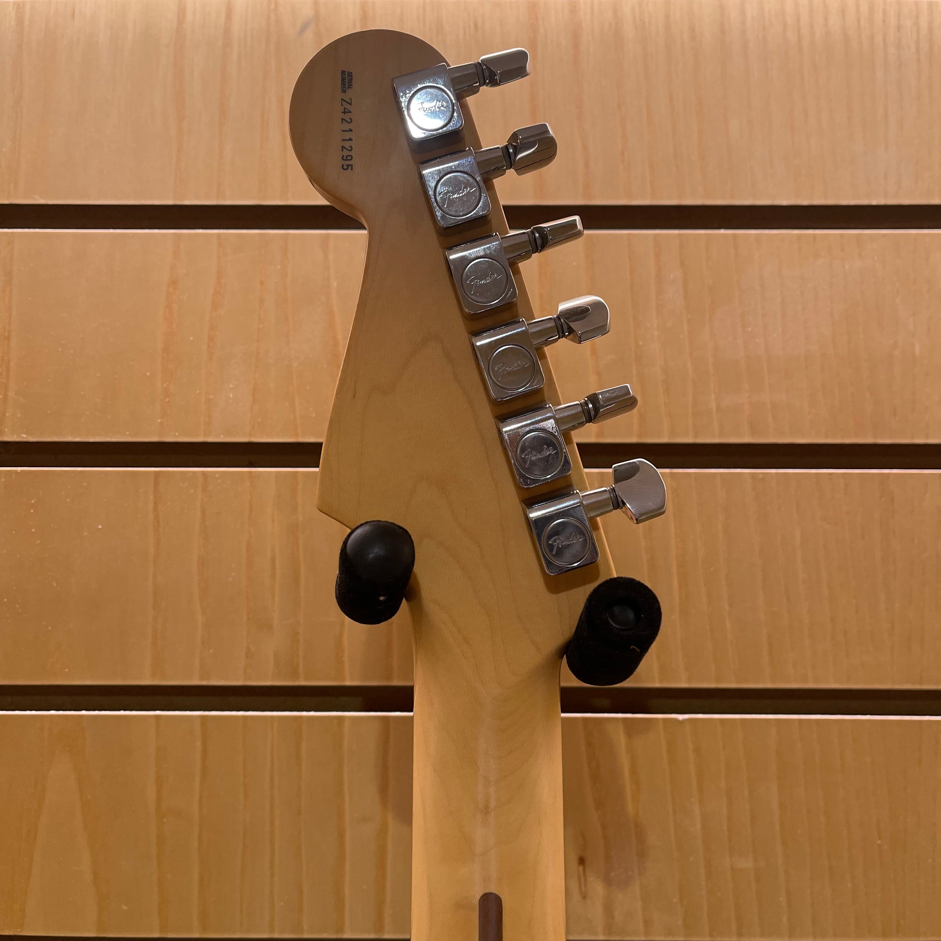 Close-up of a guitar headstock with tuning pegs on a wooden background