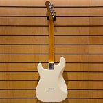White electric guitar with a wooden neck against a wooden slat background